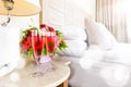 Two glasses of rose champagne with light festive bokeh in the upscale hotel room. Dating, romance, honeymoon, valentine