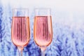 Two glasses of rose champagne with winter snowy forest bokeh as a background Royalty Free Stock Photo