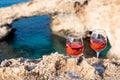 Two glasses of rose dry white wine served on rocks in blue sea bay with Love Bridge on background near Ayia Napa touristic town on Royalty Free Stock Photo