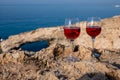 Two glasses of rose dry white wine served on rocks in blue sea bay with Love Bridge on background near Ayia Napa touristic town on Royalty Free Stock Photo