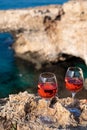 Two glasses of rose dry white wine served on rocks in blue sea bay with Love Bridge on background near Ayia Napa touristic town on Royalty Free Stock Photo