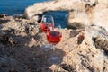 Two glasses of rose dry white wine served on rocks in blue sea bay with Love Bridge on background near Ayia Napa touristic town on Royalty Free Stock Photo