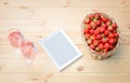 Two glasses of rose wine, white frame and ripe red strawberries in wicker basket on  wooden table Royalty Free Stock Photo