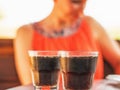 Two glasses of soda on the table and a woman in the background. Royalty Free Stock Photo