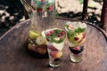 Two glasses of soft drink with a splash and spray water seasonal fruit stand on the wooden surface of the table in the garden Royalty Free Stock Photo