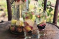 Two glasses of soft drink with a splash and spray water seasonal fruit stand on the wooden surface of the table in the garden Royalty Free Stock Photo