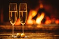 Two glasses of sparkling champagne in front of warm fireplace. C Royalty Free Stock Photo