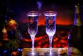 Two glasses of sparkling champagne in front of warm fireplace. Cozy relaxed magical atmosphere in a chalet house by the Royalty Free Stock Photo