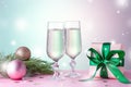 Two glasses of sparkling wine, gift box with bow, decorations. Composition in pink and green for Christmas, New Year. Still life Royalty Free Stock Photo