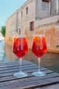 Two glasses of Spritz Veneziano cocktail served near the Venetian canal.