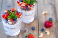 Two glasses of strawberry parfait made from fresh fruit, yogurt, blueberries, flax seeds and muesli on a wooden background. Royalty Free Stock Photo