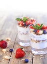 Two glasses of strawberry parfait made from fresh fruit, yogurt, blueberries, flax seeds and muesli on a wooden background. Royalty Free Stock Photo