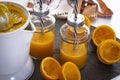 Two glasses on the table with orange juice and straw, electric squeezer and oranges cut in half Royalty Free Stock Photo