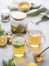 Two glasses of tea with fresh lemon, honey, mint and ginger on a light background with teapot and morning light close up Royalty Free Stock Photo