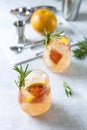 Two glasses of tequila cocktail or cold lemonade with grapefruit juice, tinted with the aroma of a fresh sprig of rosemary Royalty Free Stock Photo