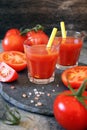 Two glasses of tomato juice, bunch of tomatoes and pink salt