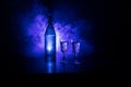 Two glasses of Vodka with bottle on dark foggy club style background with glowing lights (Laser, Stobe) Multi colored. Club drinks Royalty Free Stock Photo