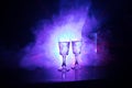 Two glasses of Vodka with bottle on dark foggy club style background with glowing lights (Laser, Stobe) Multi colored. Club drinks