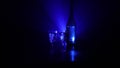 Two glasses of Vodka with bottle on dark foggy club style background with glowing lights Laser, Stobe Multi colored. Club drinks