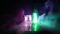 Two glasses of Vodka with bottle on dark foggy club style background with glowing lights Laser, Stobe Multi colored. Club drinks