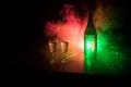 Two glasses of Vodka with bottle on dark foggy club style background with glowing lights (Laser, Stobe) Multi colored. Club drinks