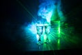 Two glasses of Vodka with bottle on dark foggy club style background with glowing lights (Laser, Stobe) Multi colored.