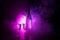 Two glasses of Vodka with bottle on dark foggy club style background with glowing lights (Laser, Stobe) Multi colored. Club drinks