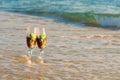 Two glasses in a wave of the sea on the beach Royalty Free Stock Photo