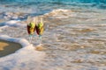 Two glasses in a wave of the sea on the beach