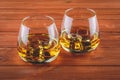 Two glasses of whiskey on a brown wooden table. A glass of bourbon with ice. Strong drink. Old brandy, cognac Royalty Free Stock Photo