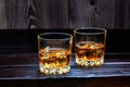 Two glasses of whiskey with ice cubes on a wooden table Royalty Free Stock Photo