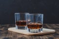 Two Glasses of whiskey with ice cubes on a wooden table/Two Glasses of whiskey with ice cubes on a wooden table. Black background Royalty Free Stock Photo