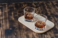 Two Glasses of whiskey with ice cubes on a wooden table/Two Glasses of whiskey with ice cubes on a wooden table. Black background Royalty Free Stock Photo