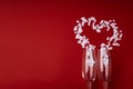 Two glasses with white hearts and splashing in heart shape on red background. Valentine's Day, love concept. Copy space. Royalty Free Stock Photo