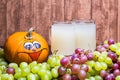 White stum together with some green and red grapes and a pumpkin photographed in front of a piece of wood Royalty Free Stock Photo