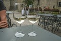 Two glasses of white wine in restaurant on the tables across restaurant exterior. Restaurant terrace.