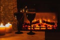 Two glasses wine with candles in front of the fireplace. Romantic atmosphere. Beautiful background with cozy magical