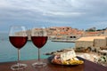 Two glasses of wine with charcuterie assortment against Dubrovnik city center background. Vacation concept. Beach and city wall in Royalty Free Stock Photo