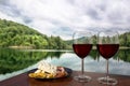 Two glasses of wine with charcuterie assortment on calm lake background in Croatia. Glass of red wine with different snacks -