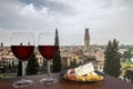 Two glasses of wine with charcuterie assortment on view of Verona, Italy. Glass of red wine with different snacks - plate with ham Royalty Free Stock Photo