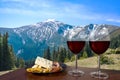 Two glasses of wine with cheese and meat assortment on view of mountains landscape. Glass of red wine with different snacks - Royalty Free Stock Photo