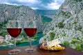 Two glasses of wine with cheese and meat snacks with view of Cetina River, mountains and old town Omis, Croatia. Cetina river Royalty Free Stock Photo