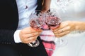 Two glasses of wine in the hands of newlyweds. Couple is clinking bocals.