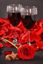 two glasses of wine, rose, petals and chocolates on a black background Royalty Free Stock Photo