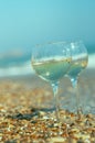 Two glasses of wine on the sand on the beach. Sparkling bokeh of pebbles on the shore Royalty Free Stock Photo