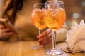 Two glasses of wine with spritz stand on a wooden table in a cafe, in the rays of the setting sun. Italian alcoholic