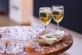 Two glasses of wine standing on a wooden, snowy table and a bowl of oysters in the foreground