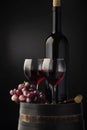 Two glasses of wine, vine, bottle and wooden barrel isolated on black gradient Royalty Free Stock Photo
