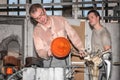 Two glassmakers creative unique works in Moser Glass Factory in Czech Republic. Transform a hot mass of glass drawn from a hot