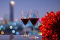 Two glasss of red wine and red roses bouquet on table with colorful city bokeh lights Royalty Free Stock Photo